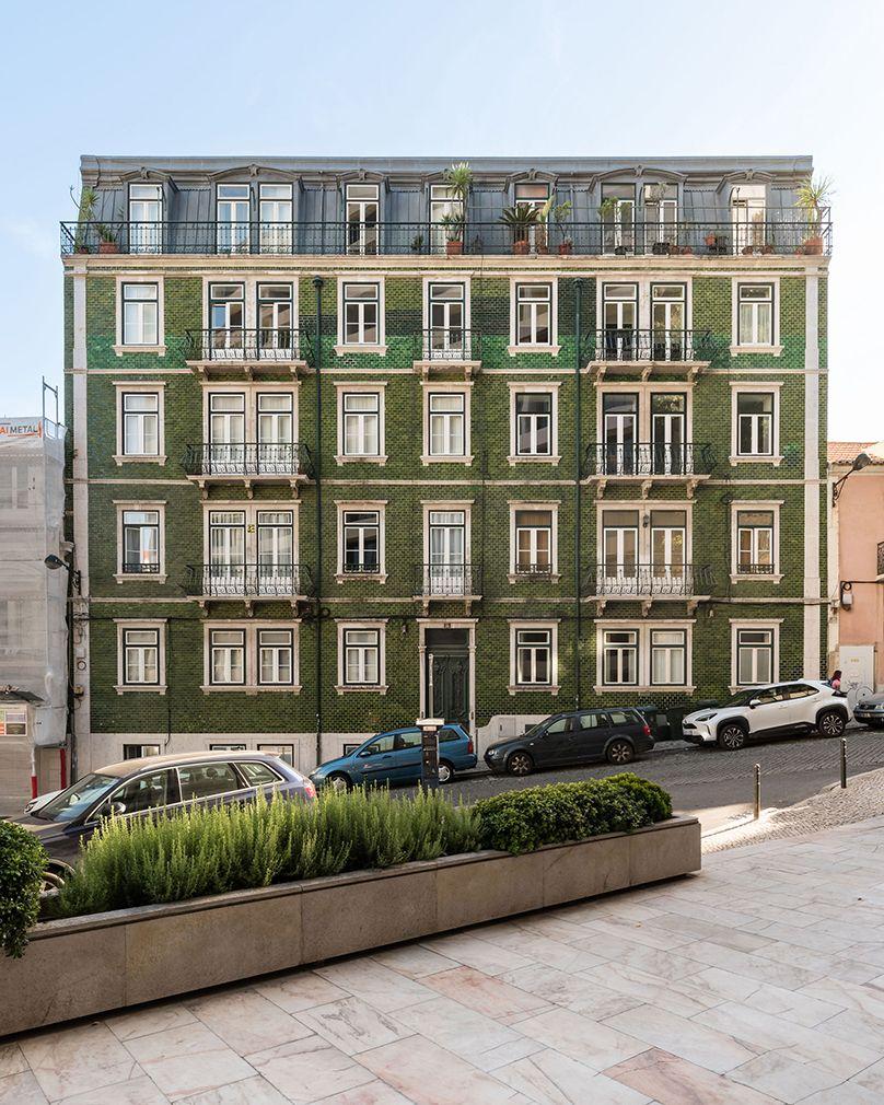 Residential building with a green azulejo facade and wrought-iron balconies in Lisbon