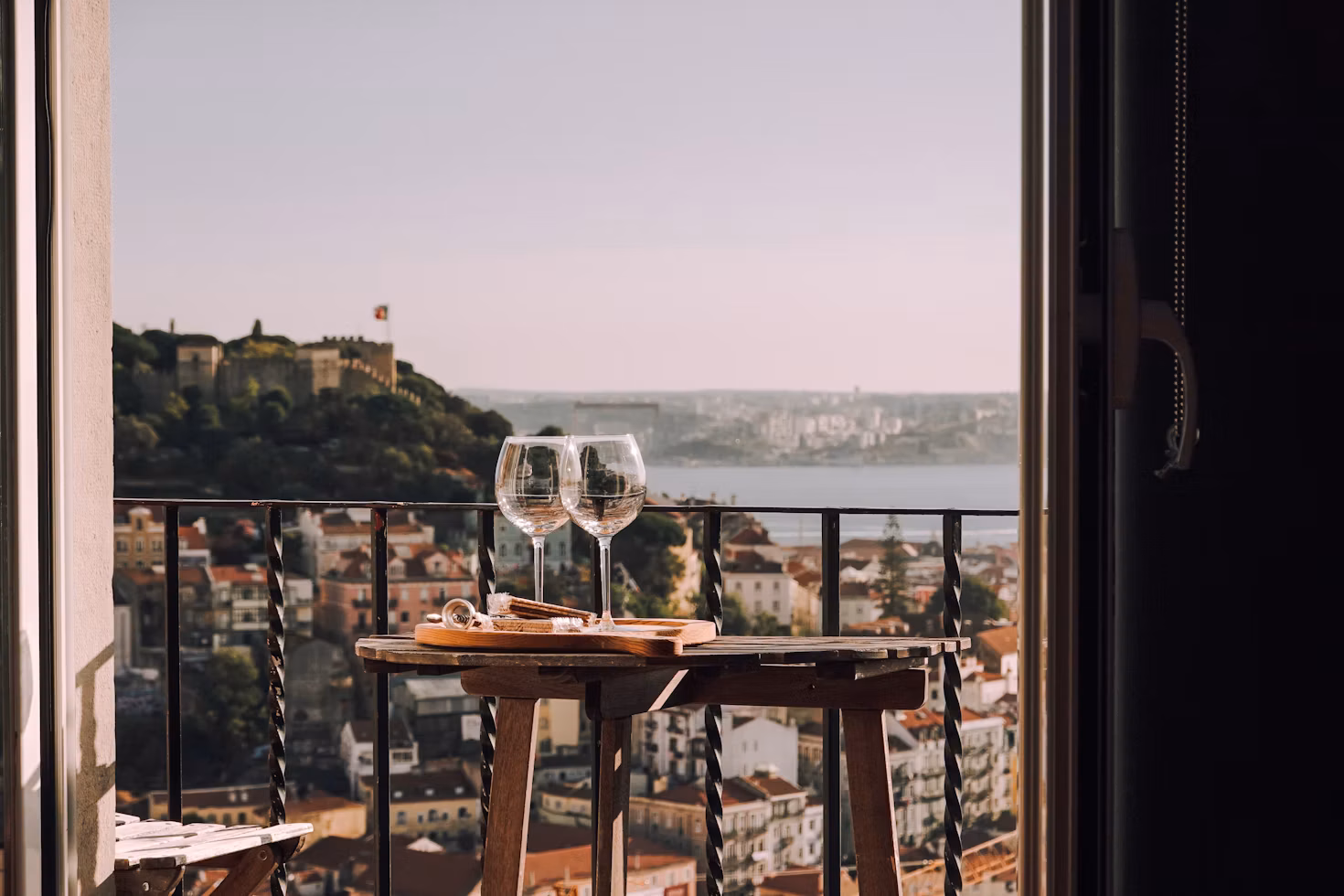 Balcony with two wine glasses overlooking São Jorge Castle and the Tagus, Lisbon