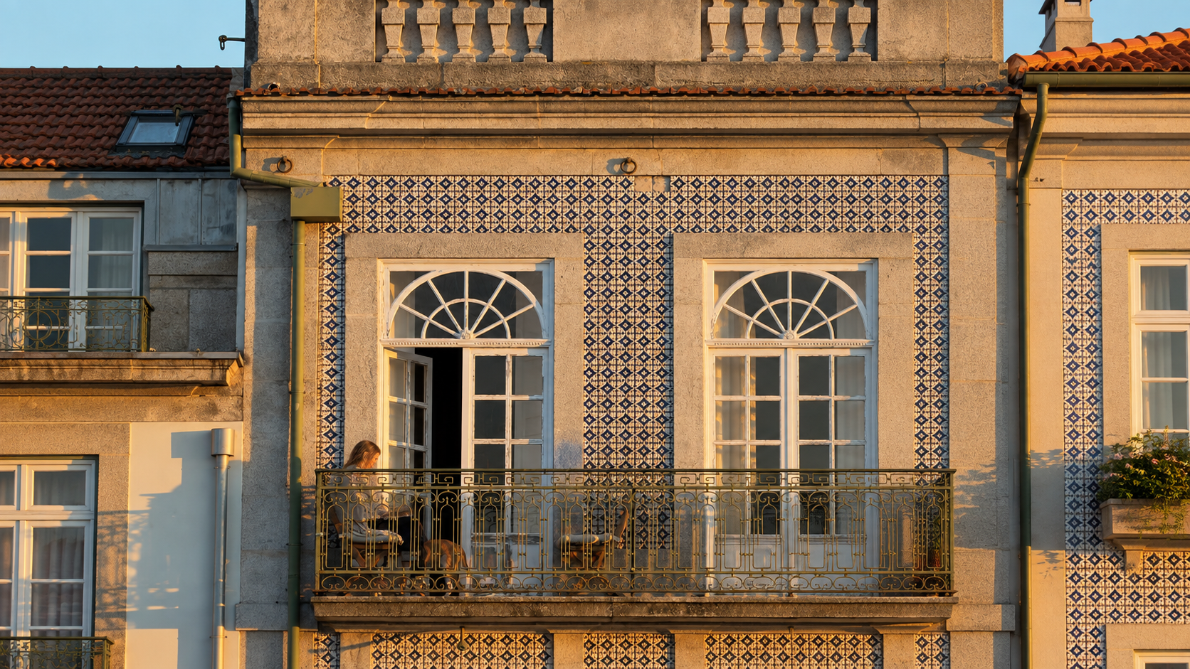 Lisbon façade with blue azulejo tiles and a wrought-iron balcony in golden evening light